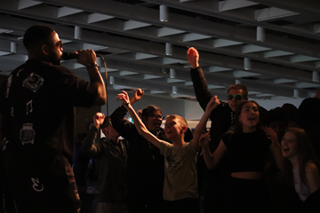 A crowd of young people listening to a person holding a microphone