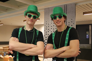 Two people dressed in green and black matching outfits.
